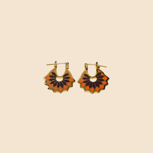 Pair of gold hoop earrings with orange and black design on a beige .Miniz flower mandala enamel earrings background