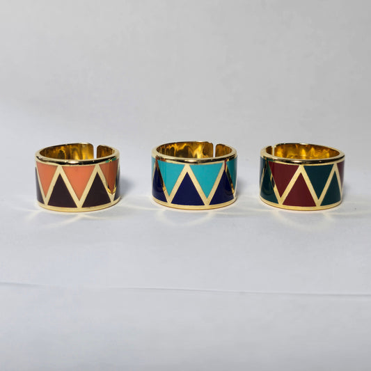 Three geometrically patterned rings with gold bands on a white background, enamel plum mocca ring gold ,Miniz jewelry rings summer uae canada lebanon united states