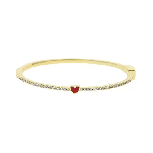 A gold-colored bracelet with a red enamel heart charm and small clear stones along its length. سوار كَفّ أنيق مزين بزركونيا
