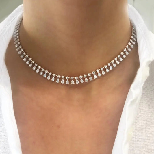 A close-up image of a woman wearing a silver-colored necklace with sparkling zirconia, likely a bridal necklace.