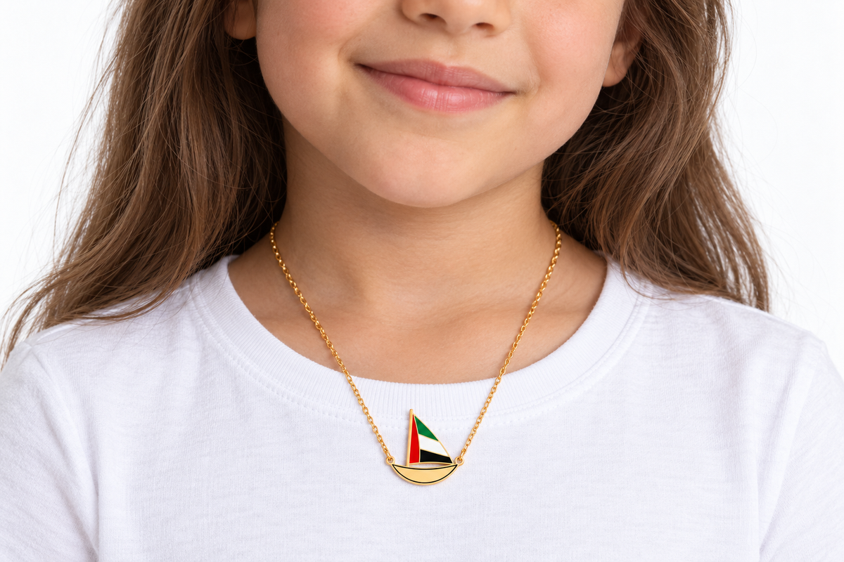 Child wearing approved Little Sail 2 × 2 cm gold plated dhow necklace, flat laser-cut hull with thin black enamel outline — generated styling image
