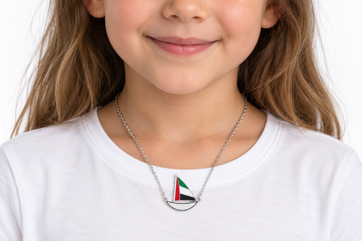 Child wearing approved Little Sail 2 × 2 cm silver finish dhow necklace, flat laser-cut hull with thin black enamel outline — generated styling image