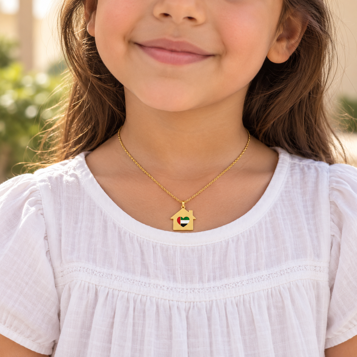 Child wearing My UAE Home 2 × 2 cm gold plated house necklace with UAE flag heart — generated styling image